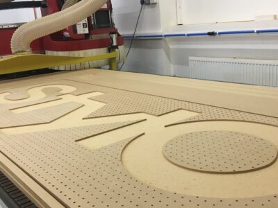 A cnc machine is making a wooden sign.
