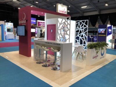A trade show booth with a white table and chairs.
