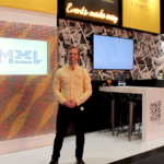 A man standing in front of a booth at a trade show.