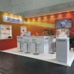 A trade show booth with stools and a bar.